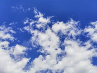 White fluffy volumetric cumulus clouds against a bright blue sky. Beautiful natural sky background. Sky backdrop for your photos