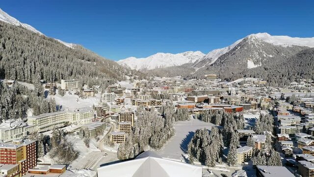 Davos, Switzerland: Aerial view of famous Swiss Alpine ski resort town in winter, buildings and slopes covered in snow - landscape panorama of Alps mountain range from above, Europe