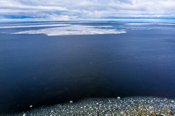 Ice blocks drifting around in a calm sea water creating interesting aerial patterns. Shot from drone