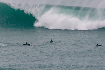 Surfer Carving and performing tricks on huge blue waves in Newquay, Cornwall - Southwest England