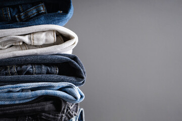 Folded jeans on gray background with place for text. Close-up.