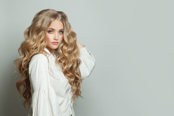 Perfect young woman with long blonde healthy curly hairdo on white background - obrazy, fototapety, plakaty