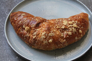 sweet French croissant, desert, puff pastry, croissant on a round plate, cone