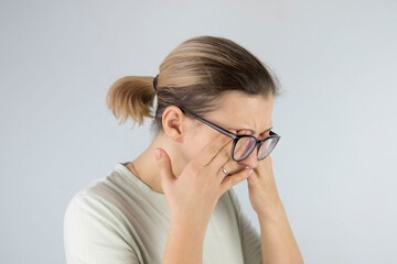 Fototapeta premium young woman rubs tired eyes from glasses, poor eyesight, vision problems.
