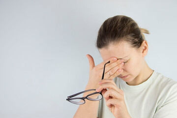 young woman rubs tired eyes from glasses, poor eyesight, vision problems.