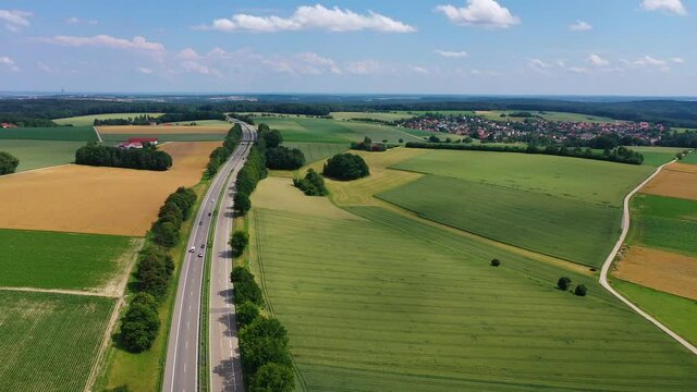 A drone flies over the German Autobahn in Bavaria. Smooth green German fields.