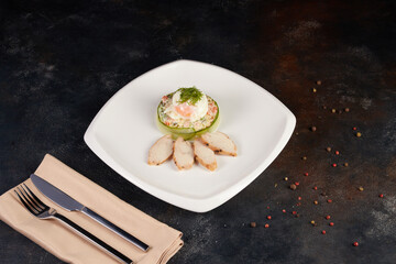 Olivier salad served on spinach leaves on a square white plate