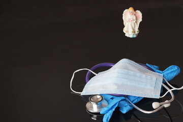 angel figurine over medical mask, gloves and phonendoscope as a symbol of hope