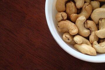 Cashew nuts in a white bowl on a wooden table background