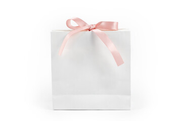 White paper shopping bag with pink bow on white background. Gift box, surprise for holiday. Present, gift, shopping and sale concept