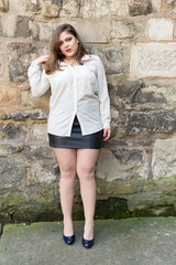 Portuguese woman in black skirt and white shirt standing by a wall