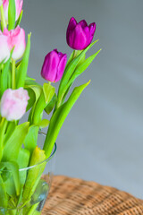 A bouquet of pink rose and purple tulip flowers inside a house close up detail view