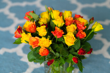 A bouquet with a lot of red orange and yellow roses on a table interior photography
