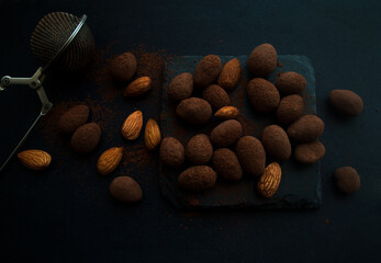 Almonds in cocoa on stone dark plate on black  background with copy space. 