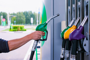 Man holds a refueling gun in his hand for refueling cars. Gas station with diesel and gasoline fuel...