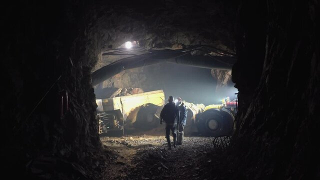 Miners talking against the backdrop of underground mining equipment.