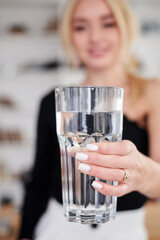 Close-up picture of huge glass of water in hands of young blond woman, standing in office room. Manager at workplace. Work process in company.Healthy drink consumption concept.Water balance.