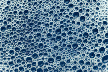 Soap bubbles on a background of blue water as a texture. Top view. Copy, empty space for text