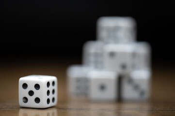 Dice showing a five and a six with a stack of dice in background on a wood table