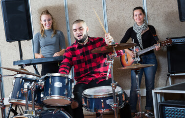 Fototapeta na wymiar Group of young musicians with expressive male drummer rehearsing in sound studio