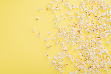 top view of crunchy popcorn scattered on yellow, cinema concept