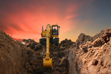 Excavators are digging the soil in the construction site on the  sunset  background