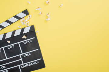 Fototapeta na wymiar top view of clapperboard near scattered popcorn on yellow, cinema concept