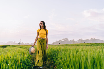 Cheerful young woman looking at green fields with bright smile