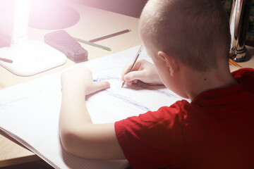 Portrait of a young boy writing in the room