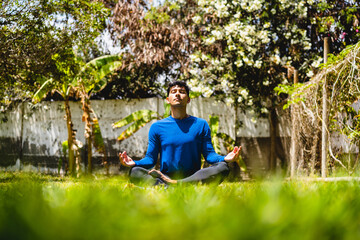 RELAXED MAN DOING EXERCISE AND MEDITATION YOGA ON NATURE OUTDOOR