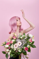 Portrait sexy young woman with pink hair, beautiful bouquet flowers in hand. Perfect hairstyle and hair coloring. Girl with beautiful eyes and long pink hair