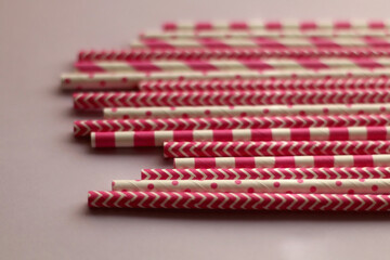Pink and white paper straws on pastel pink background. Selective focus.