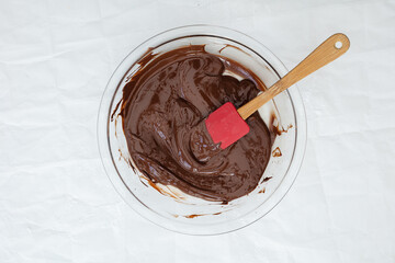 Melted chocolate in a bowl with a red spatula