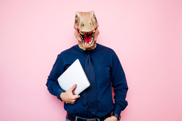 Euphoric man with dinosaur head using laptop