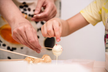Obraz na płótnie Canvas Mom and child together themselves cooking of cake pops. Home cooking, family concept, handmade food