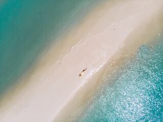 Slim girl in a yellow sexy tight bikini is sunbathing on the sand beach on Phuket island in Thailand. Top view aerial photo