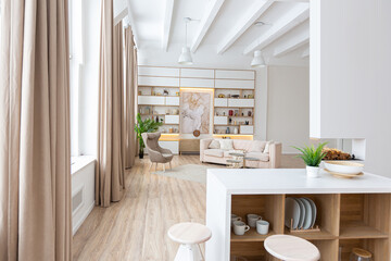 Fototapeta na wymiar interior design spacious bright studio apartment in Scandinavian style and warm pastel white and beige colors. trendy furniture in the living area and modern details in the kitchen area.