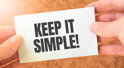 keep it simple word inscription on white card paper sheet in hands of a businessman. recap concept....