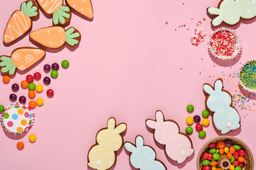 Easter baking background. Easter multicolored gingerbread, candy, scattered confectionery topping dressing and gift box on pink background. Celebratory background concept. Space for text.