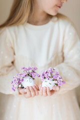kid holding hands Cute Easter eggs with drawn faces and floral purple wreath