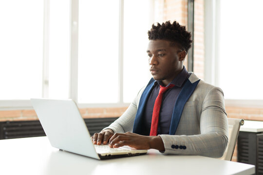 handsome young african man in office with laptop 