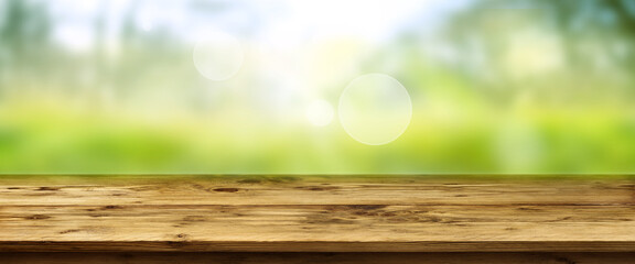 Blurred green landscape with shining bokeh and wooden table. Horizontal spring background with...