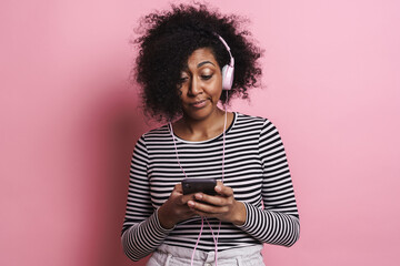 Confused african girl listening music with cellphone and headphones