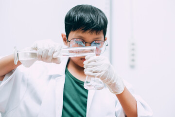 A Student Pouring Liquid in the Beaker. Conducting Experiments in a Laboratory