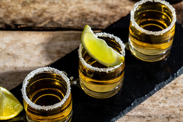 Tequila shots with salt and lime Mexican national drink. Golden tequila shots. Mexican national...