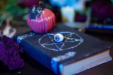 A black book with a pentagram on the cover lies on the table. The concept of an altar for carrying...