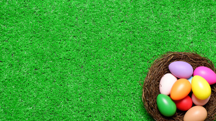 Multi colored easter eggs in birds nest on green grass lawn background top view with copy space. Easter holiday banner, card, poster, voucher, invitation, header template