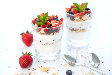 Two glasses of strawberry parfait made with fresh fruit, yogurt, blueberries, flax seeds and muesli, white background. Healthy Eating Concept