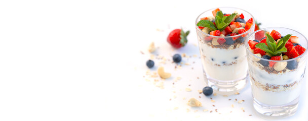 Banner. Two glasses of strawberry parfait made with fresh fruit, yogurt, blueberries, flax seeds and muesli, white background. Healthy Eating. Copy space