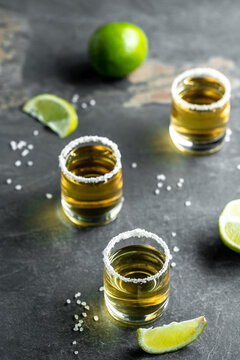 shots of gold Mexican tequila with lime and salt. Alcoholic Mexican national drink. vertical image